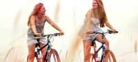 Imagem de duas jovens ciclistas. A imagem ilustra que podes fazer praticamente tudo mesmo quando estás com o período: andar de bicicleta, correr, fazer exercício, nadar, etc.